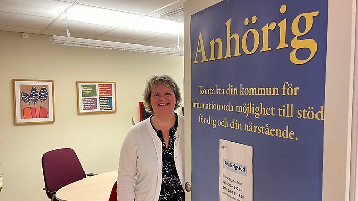 Susanne Hagelkvist är anhörigkonsulent i Perstorps kommun. Hon står v id en dörr med en affisch som det står anhörig på.
