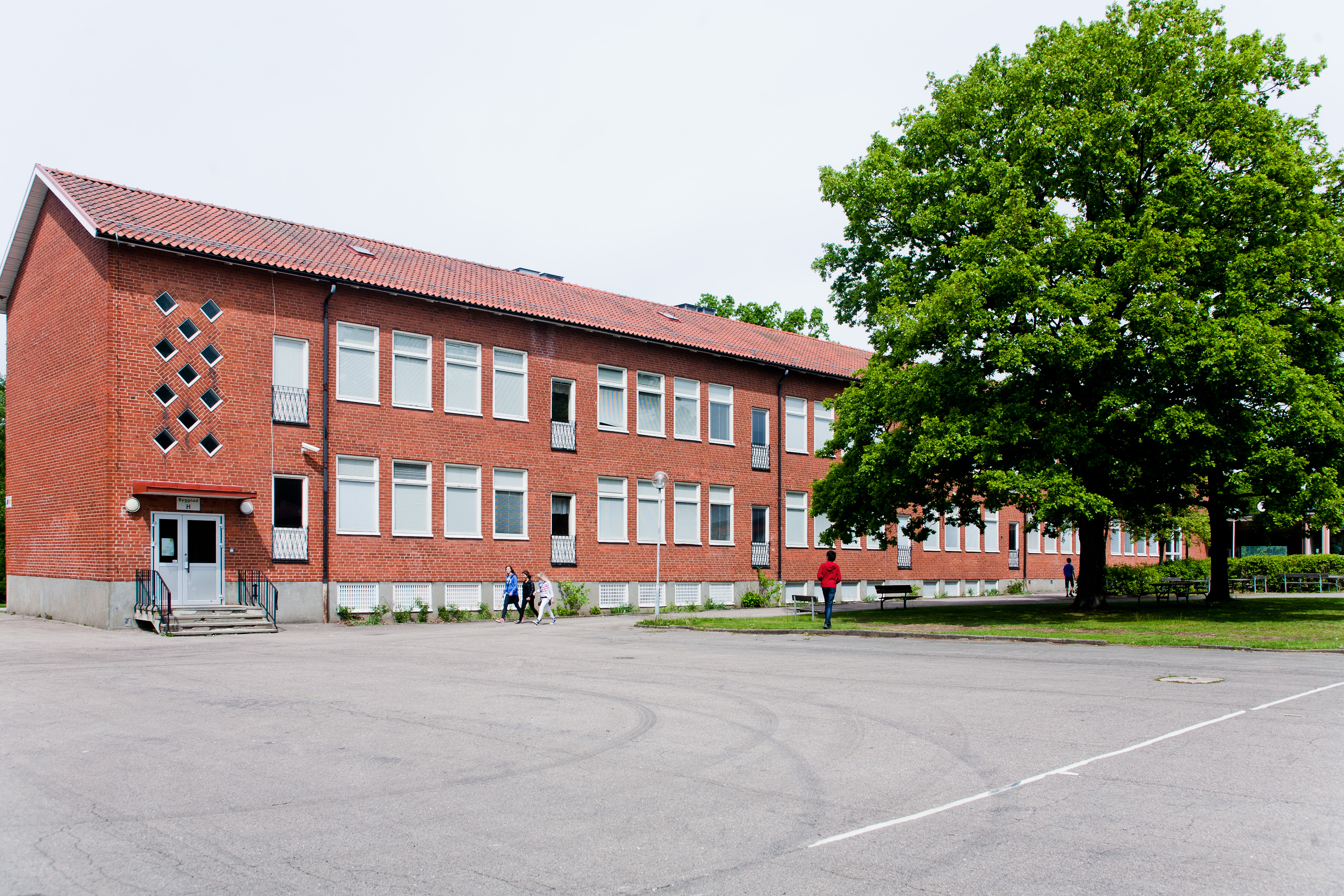 Bild som visar en skola med några elever utanför 