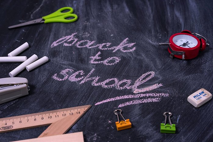 Arrangemang av skolmaterial på griffeltavla där texten back to school står skriven