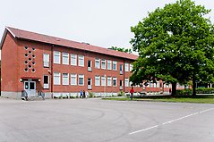 Bild som visar en skola med några elever utanför 