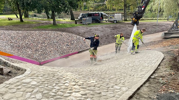 Stenar har lagts i slänten vid gångtunneln under Oderljungavägen på sidan som vätter mot Folkets Park. Personal sopar fogsand.